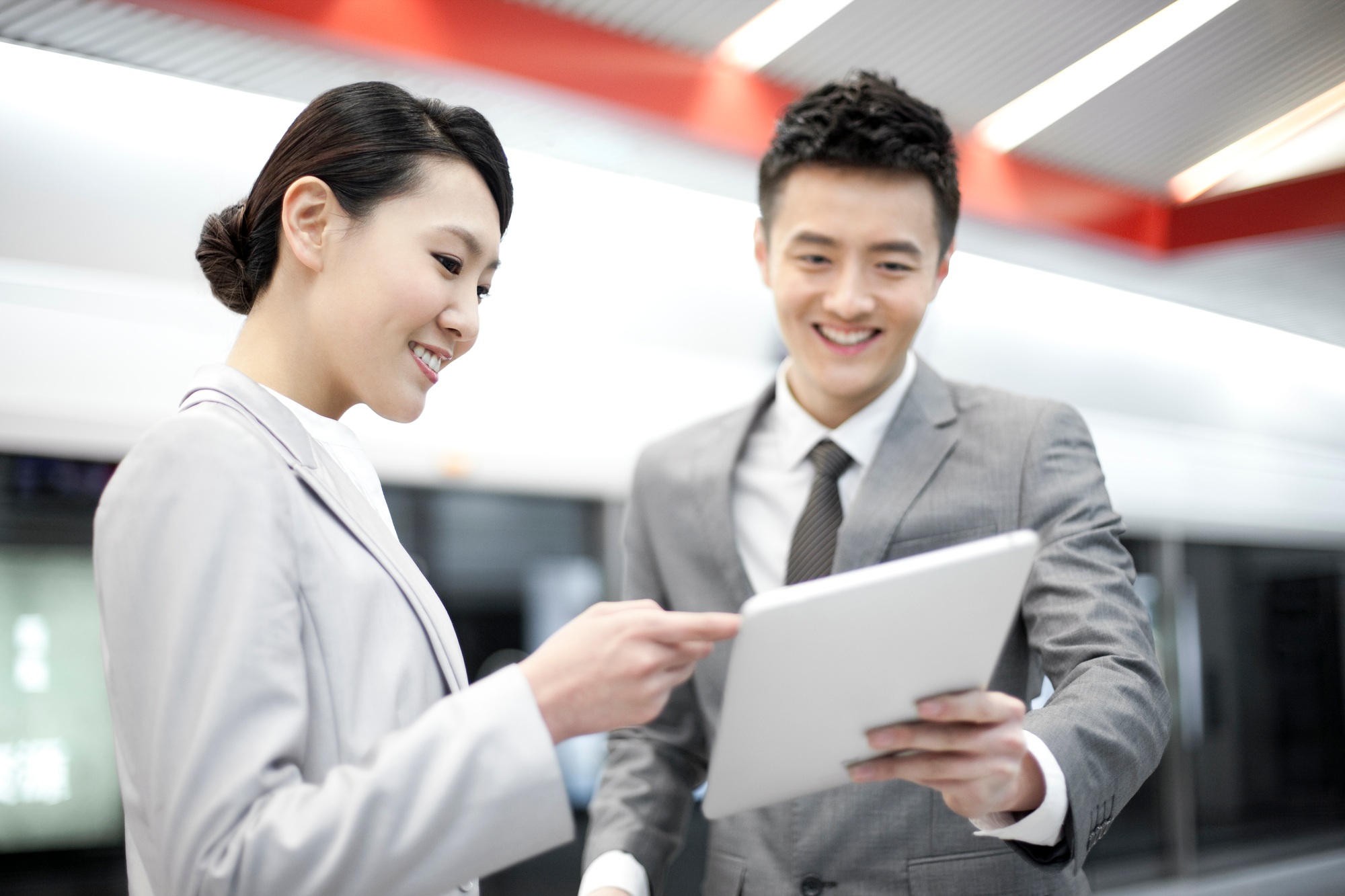 Young business partners with digital tablet on subway platform