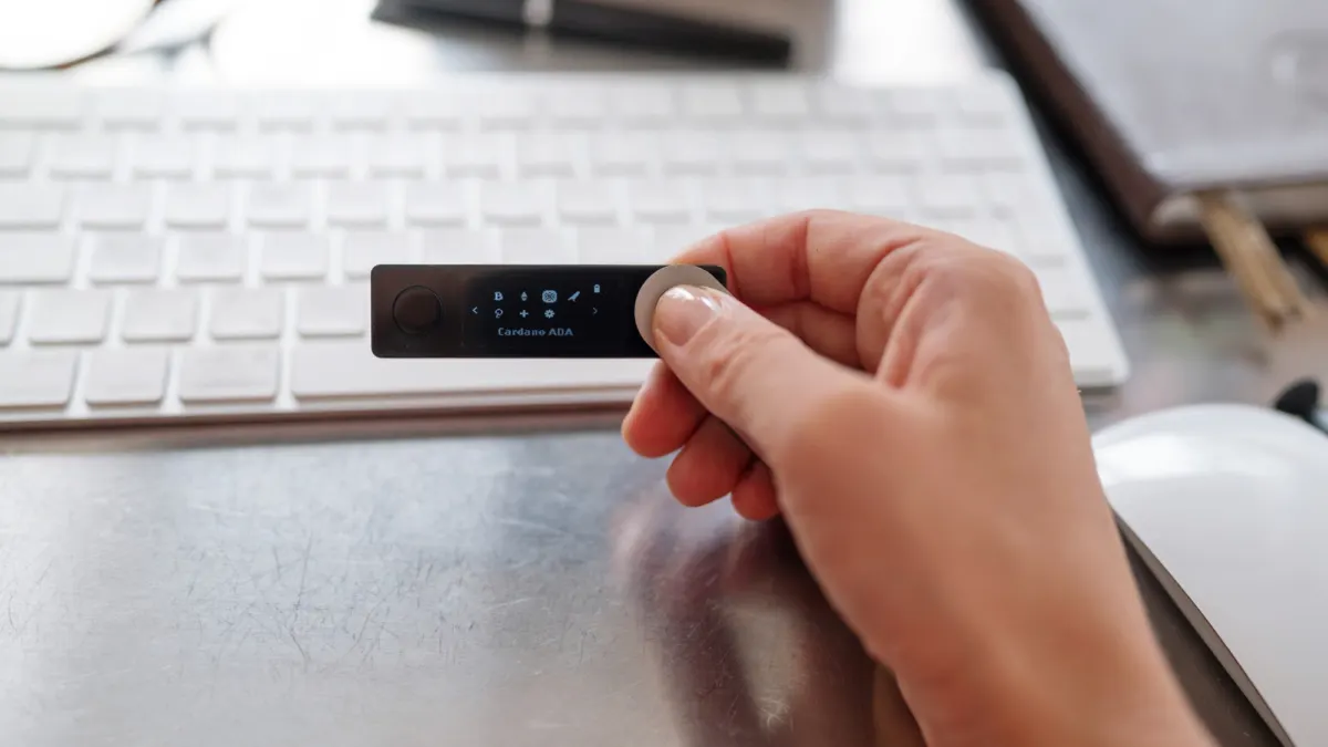Hand holding a small hardware crypto wallet device used for offline cold storage