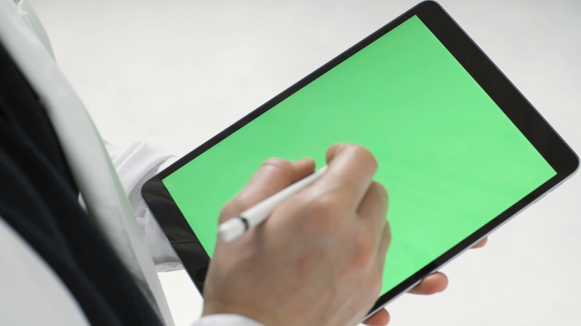 Close up of modern black tablet with green screen and a man tapping on it with a stylus, modern
