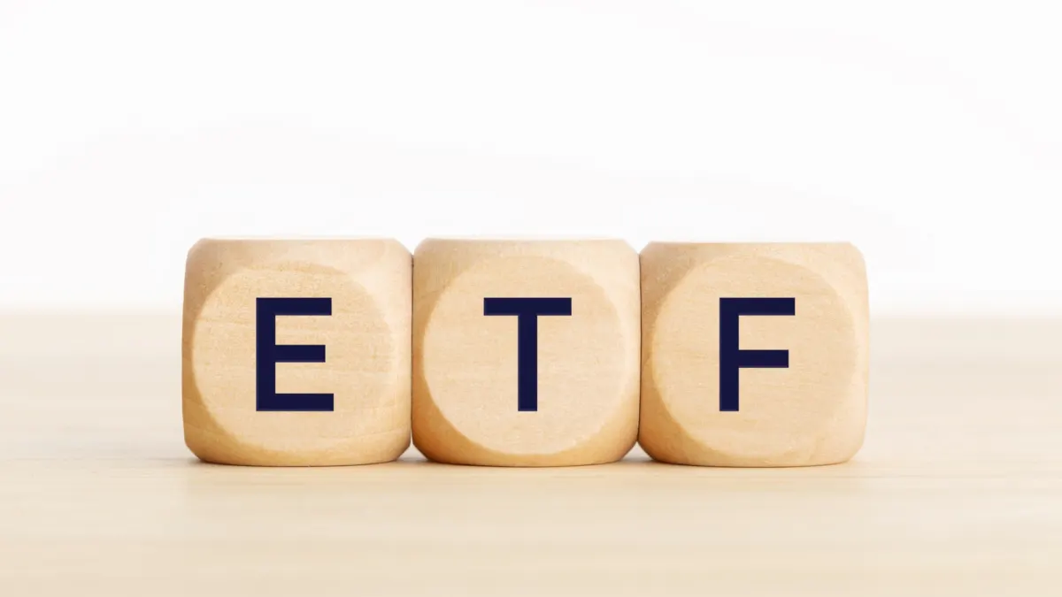 Three wooden cubes spelling ETF on a light wooden table against a white background