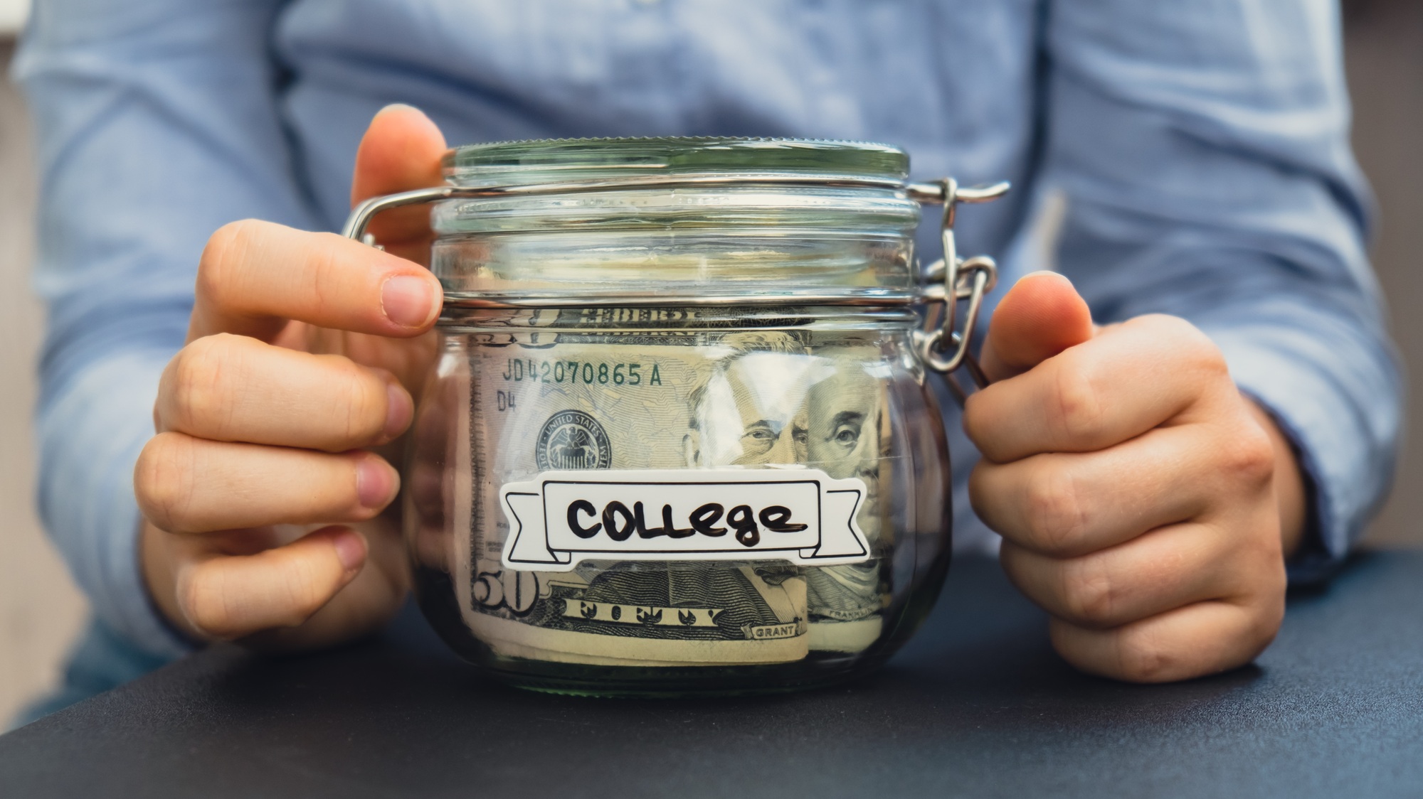 Unrecognizable woman holding Saving Money In Glass Jar filled with Dollars banknotes. COLLEGE