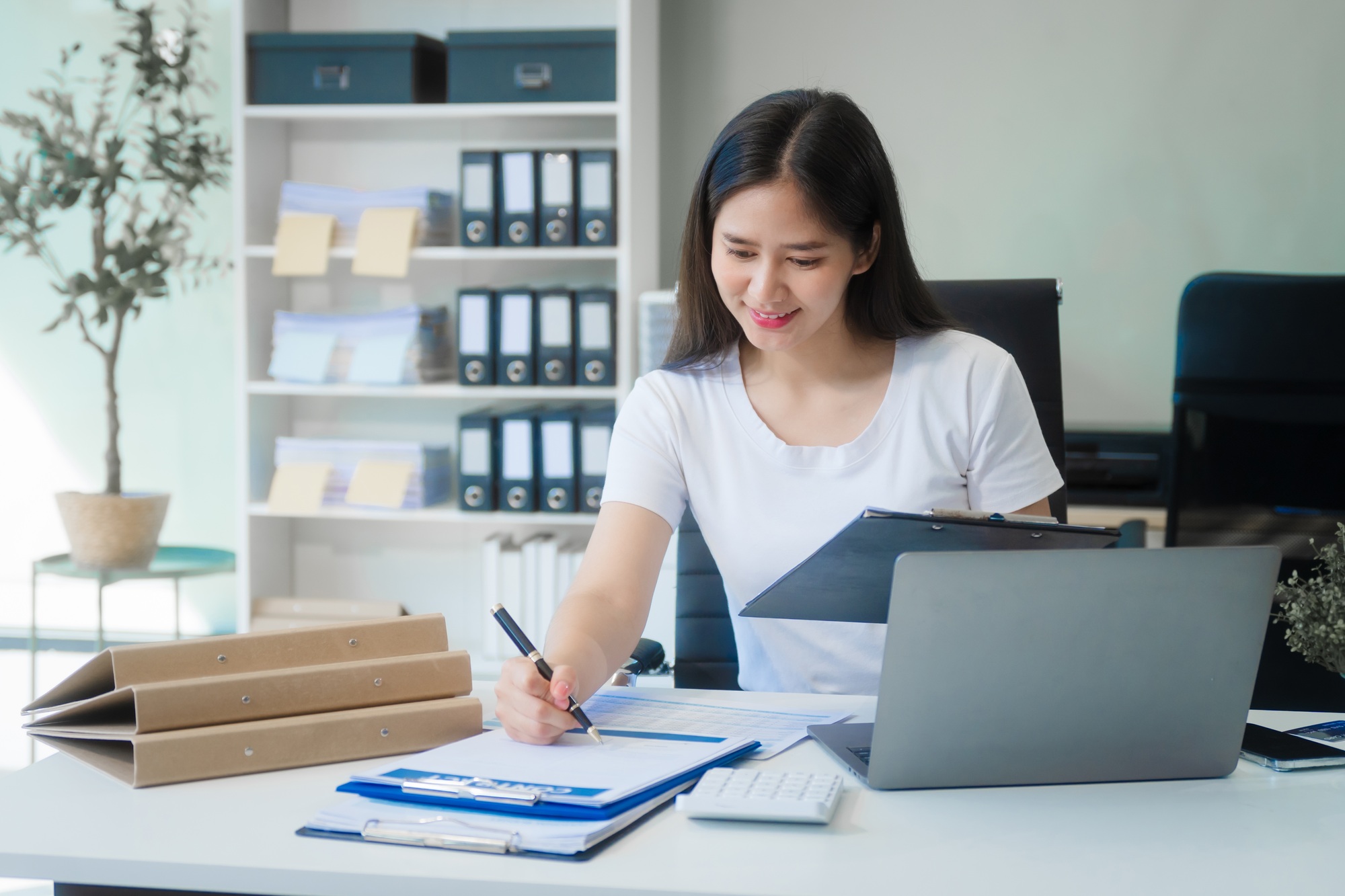 Young Asian woman at desk, analyzing credit reports, financial charts, and assessing credit risks.