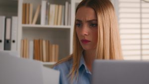 Serious frowning Caucasian woman girl at home office desk accounting job manage personal finances