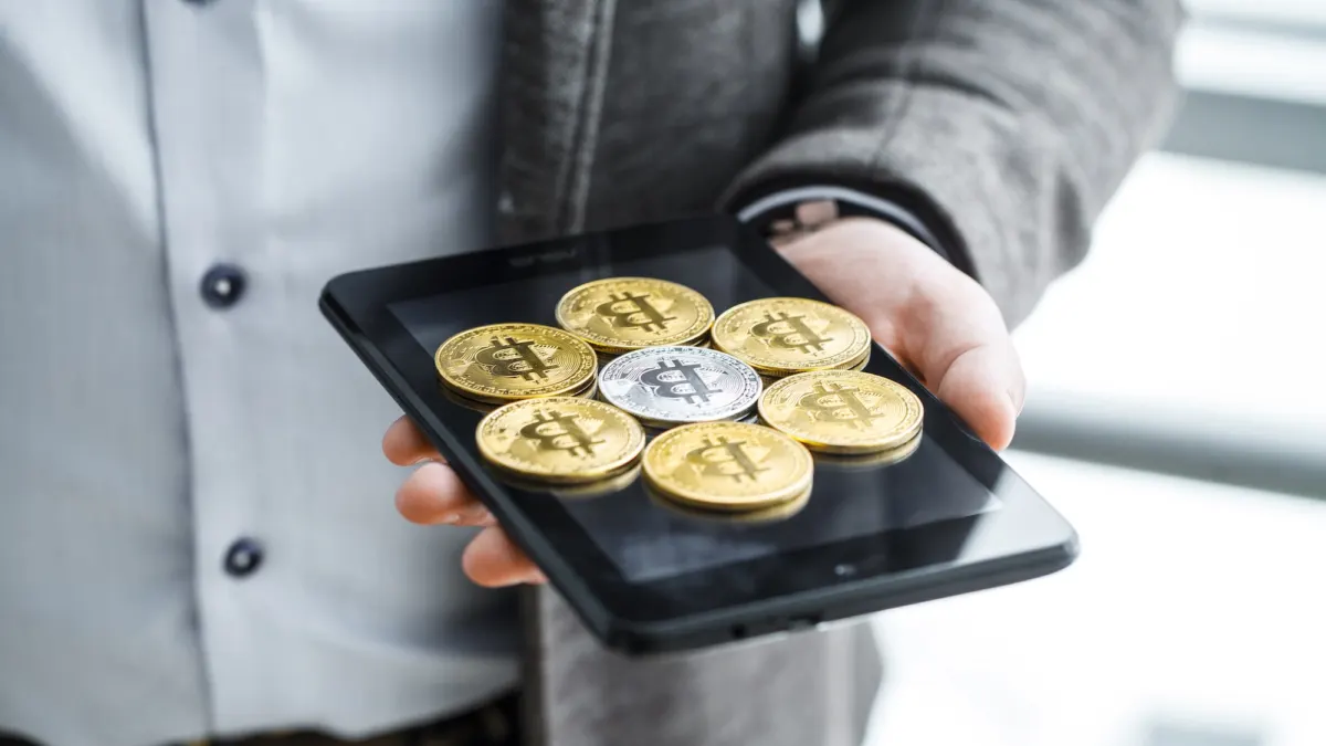 Finger pressing a bitcoin buy button on a tablet screen